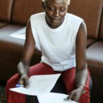 Professional woman reviewing documents in a modern office setting with a laptop.